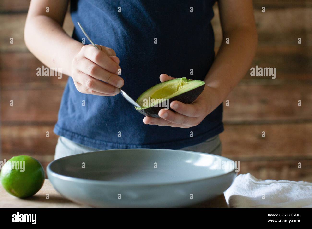 Garçon en chemise bleue scooping avacado dans un bol gris Banque D'Images