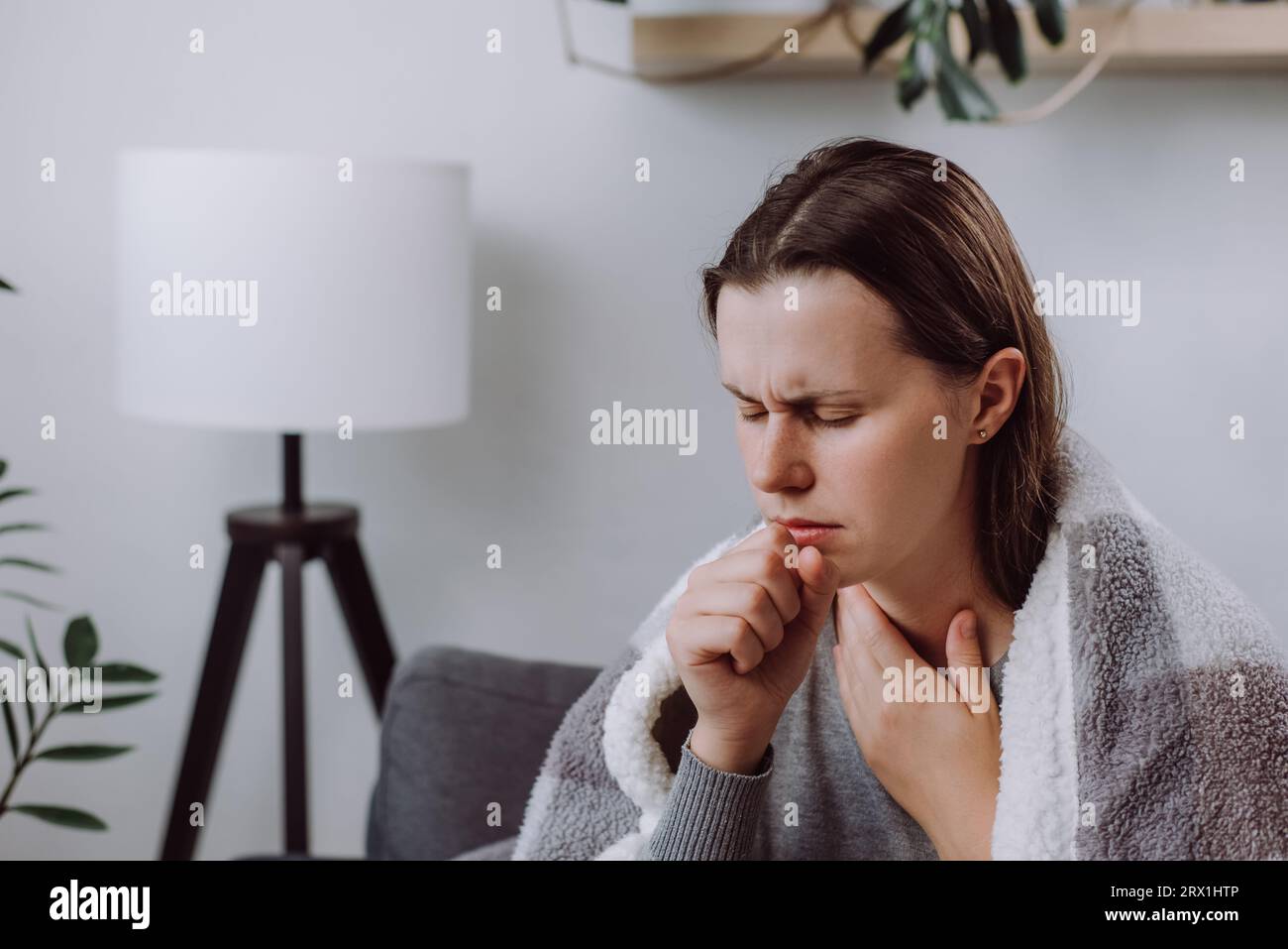 Bouleversée jeune femme malade touchant des glandes du cou gonflées douloureuses, souffrant d'une infection de la gorge, malsaine femme caucasienne triste couvert de plaid assis sur Banque D'Images