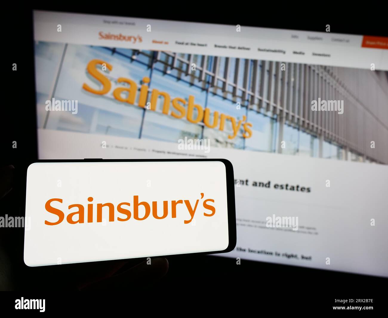 Personne tenant le téléphone portable avec le logo de la compagnie de supermarché britannique J Sainsbury plc sur l'écran devant la page Web de l'entreprise. Concentrez-vous sur l'affichage du téléphone. Banque D'Images