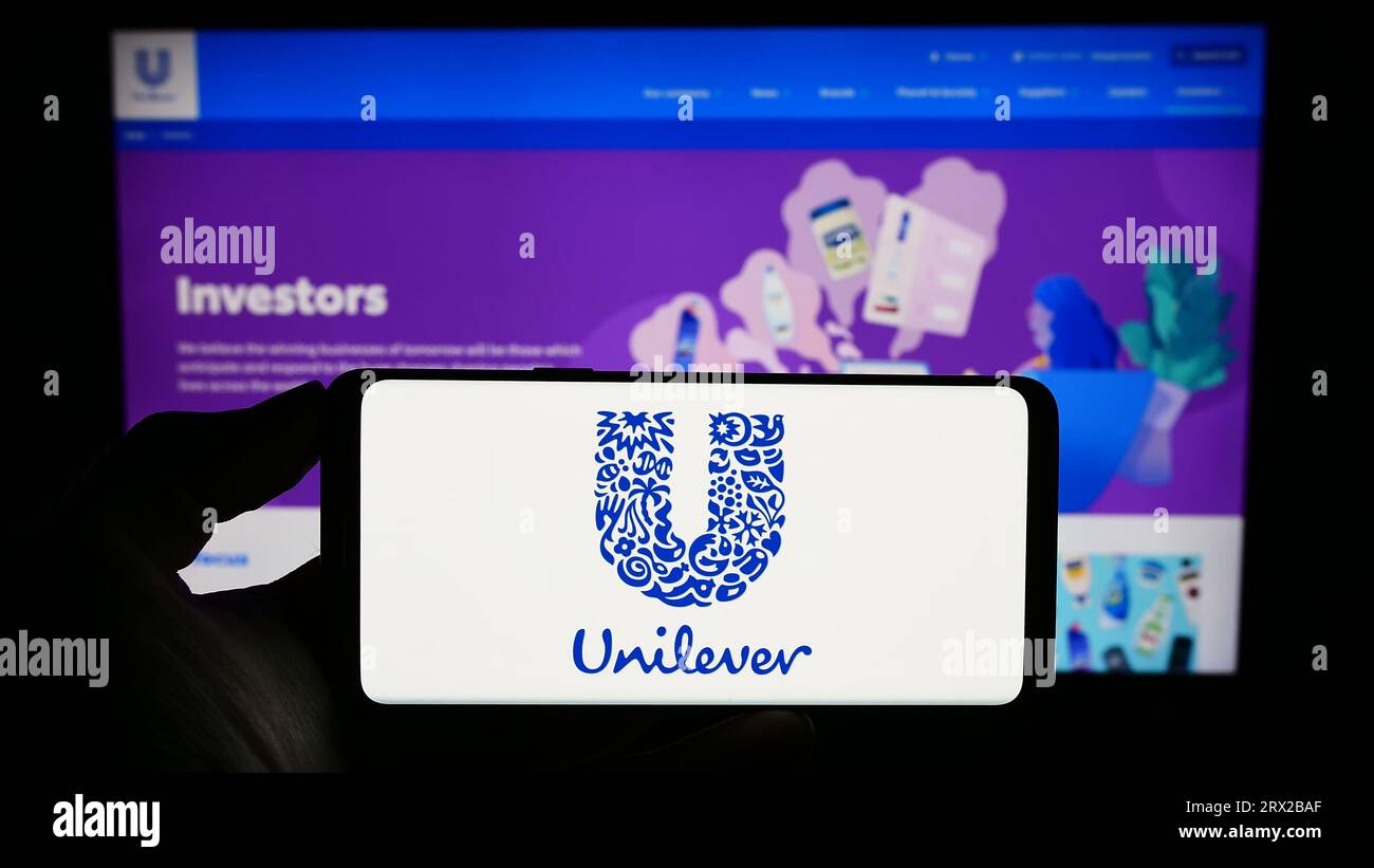 Personne tenant un smartphone avec le logo de la société britannique de biens de consommation Unilever plc sur l'écran devant le site Web. Concentrez-vous sur l'affichage du téléphone. Banque D'Images
