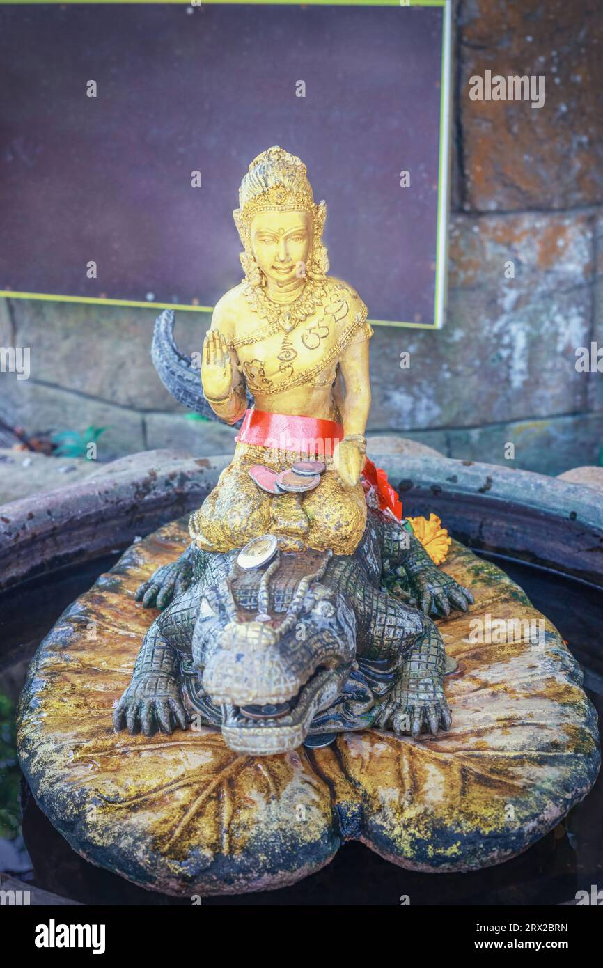 Vieille statue dorée déesse Dharani Mata sur crocodile dans le temple thaïlandais. Sculpture en or antique de la Terre mère sur alligator dans le sanctuaire à Phuket, Thaïlande Banque D'Images