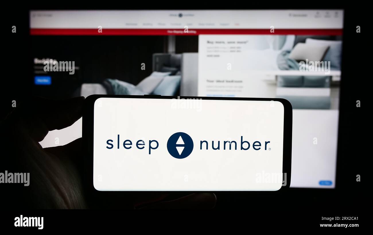 Personne tenant un smartphone avec le logo de la société de literie américaine Sleep Number Corporation sur l'écran devant le site Web. Concentrez-vous sur l'affichage du téléphone. Banque D'Images