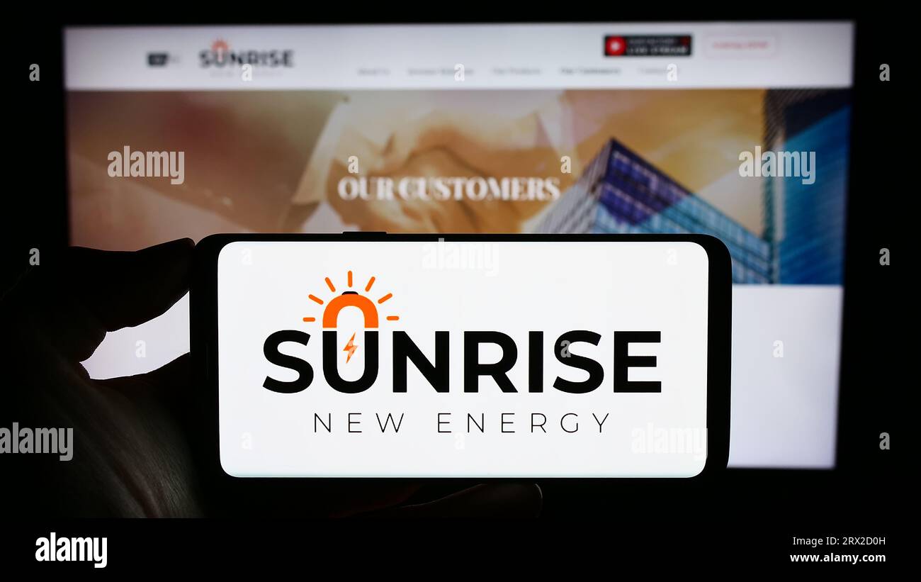 Personne tenant le smartphone avec le logo de la société chinoise Sunrise New Energy Co. Ltd. Sur l'écran en face du site Web. Concentrez-vous sur l'affichage du téléphone. Banque D'Images