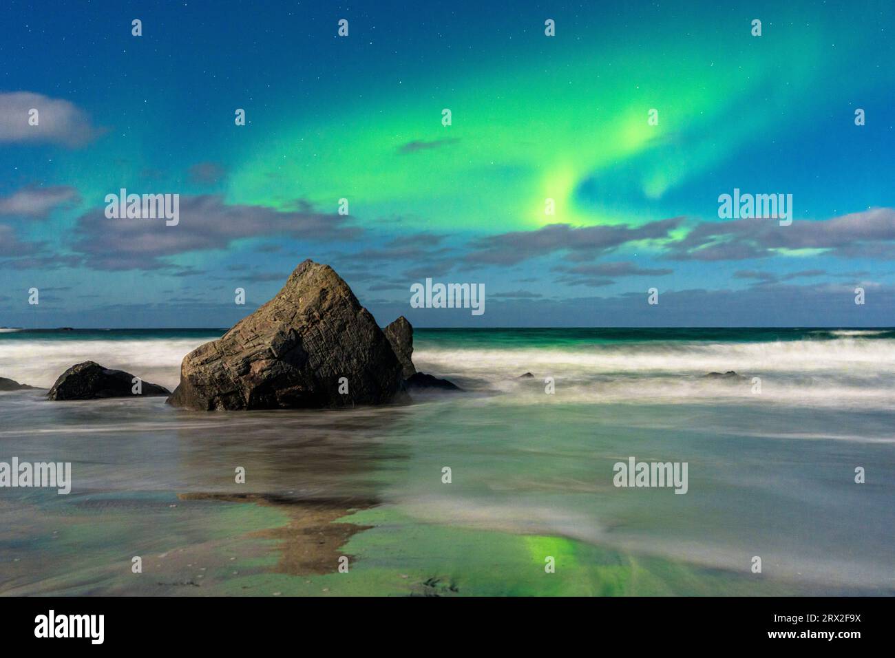 Vagues s'écrasant sur des rochers sous un ciel lumineux avec te Aurora Borealis (aurores boréales), plage de Skagsanden, Ramberg, îles Lofoten, Nordland, Norvège Banque D'Images