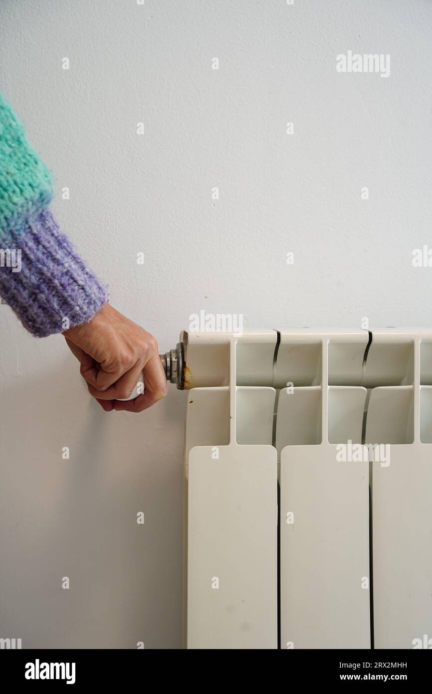 Femme ajustant la température sur le radiateur de chauffage. Inflation des prix de l'électricité et du gaz. Banque D'Images