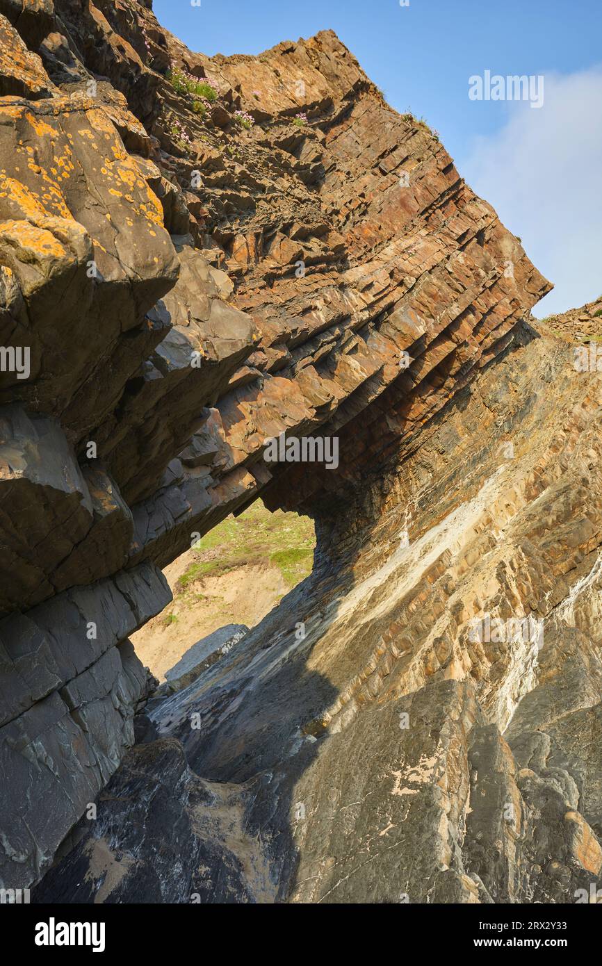 Vue ensoleillée d'une arche rocheuse, formée de plusieurs couches de roches sédimentaires rouges, à Hartland Quay, sur la côte atlantique du Devon, en Angleterre Banque D'Images