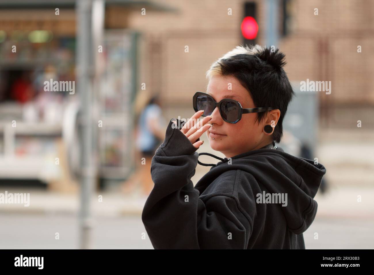 Jeune femme avec un style alternatif agitant en attendant que le feu de circulation devienne vert à Alicante, Espagne Banque D'Images