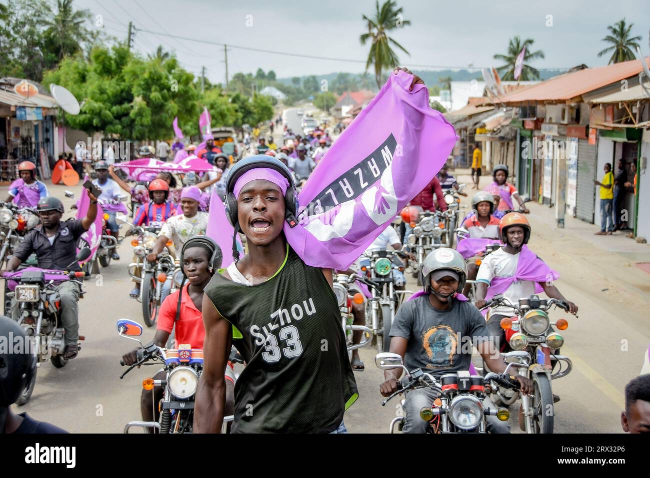 Des partisans du parti d'opposition tanzanien, ACT Wazalendo, brandissent les drapeaux du parti sur une moto lors de leur rassemblement politique dans le district de Kilwa, à Lindi reg Banque D'Images