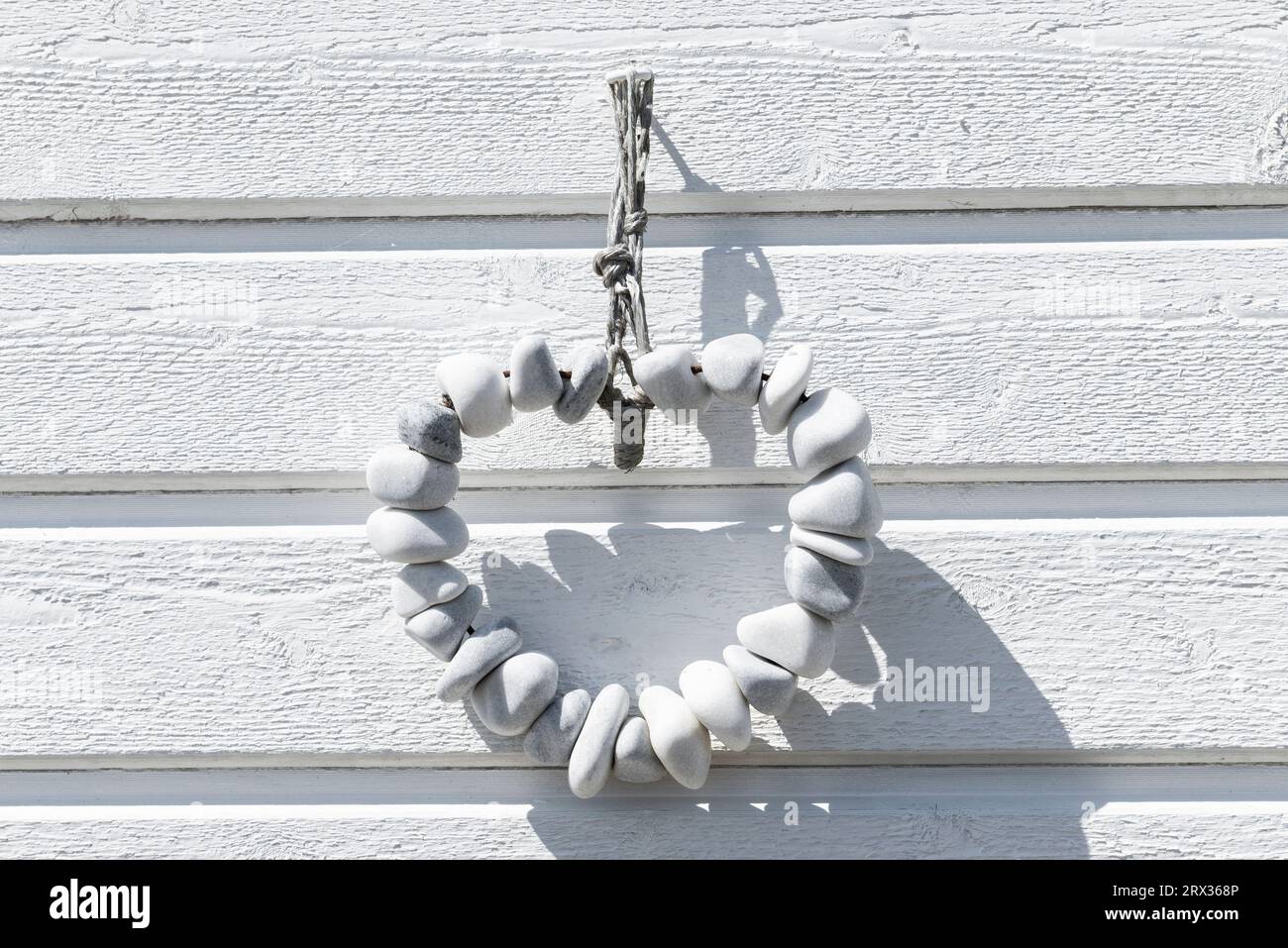 Chaîne de galets blancs en forme de cœur devant la façade en bois blanc d'une cabane de baignade sur la plage de Skanör med Falsterbo, Skåne, Suède Banque D'Images