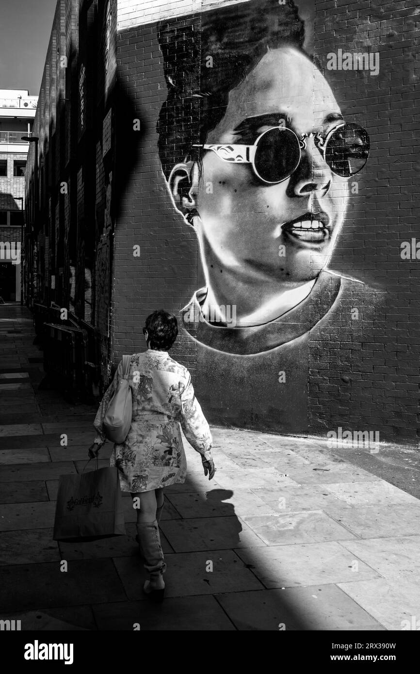 Une femme passe devant Some Colourful Street Art, Shoreditch, Londres, Royaume-Uni. Banque D'Images