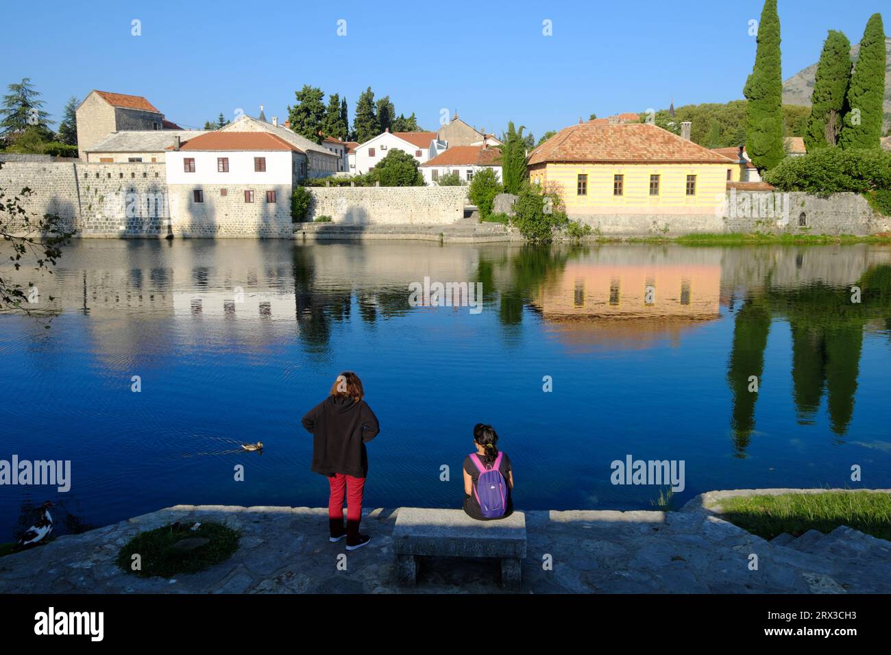 Deux touristes au bord de la rivière en face de la vieille ville de Trebinje, Bosnie-Herzégovine Banque D'Images