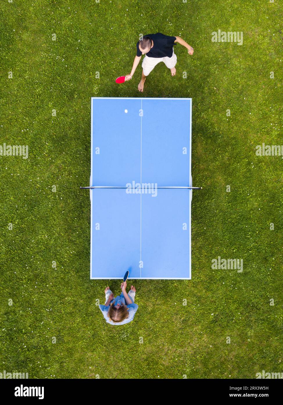 Vue aérienne personnes jouant ping-pong match en plein air. Vue de dessus deux garçons jouant au tennis de table sur une pelouse en herbe verte. Vue aérienne sport de plein air Banque D'Images