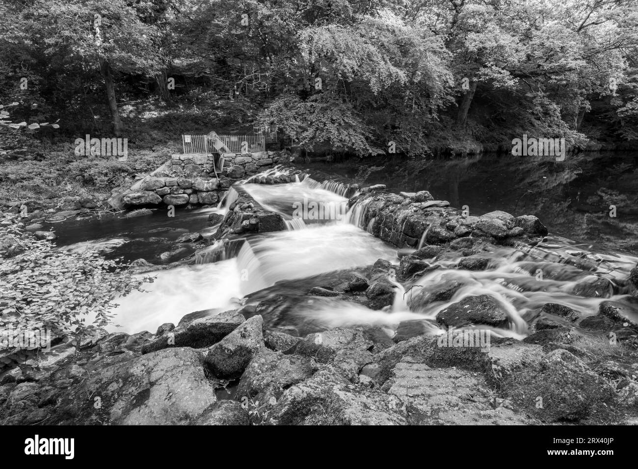 Longue exposition de la rivière Teign qui coule à travers le déversoir du château de Drogo dans le parc national de Dartmoor Banque D'Images