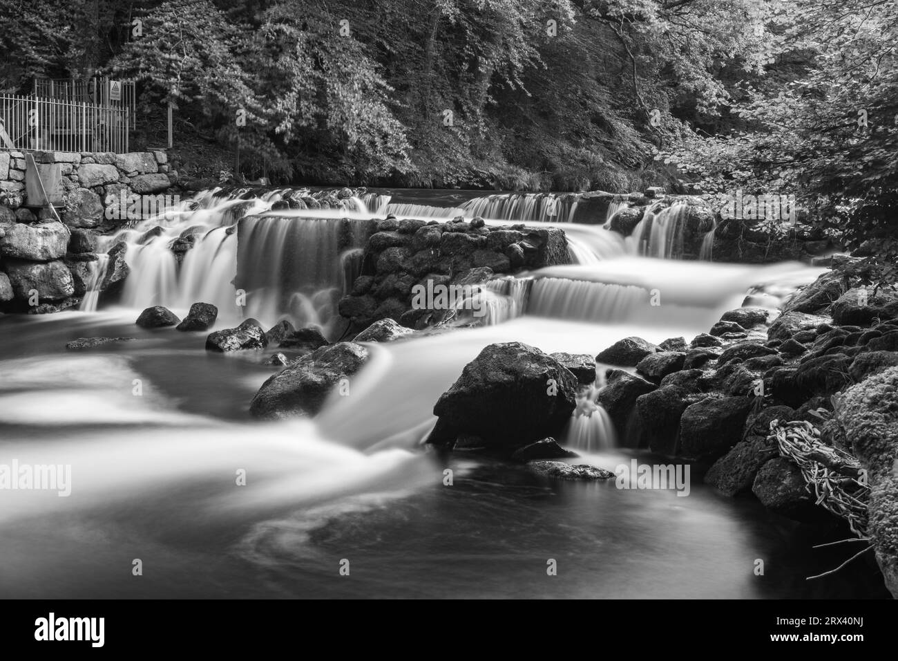 Longue exposition de la rivière Teign qui coule à travers le déversoir du château de Drogo dans le parc national de Dartmoor Banque D'Images