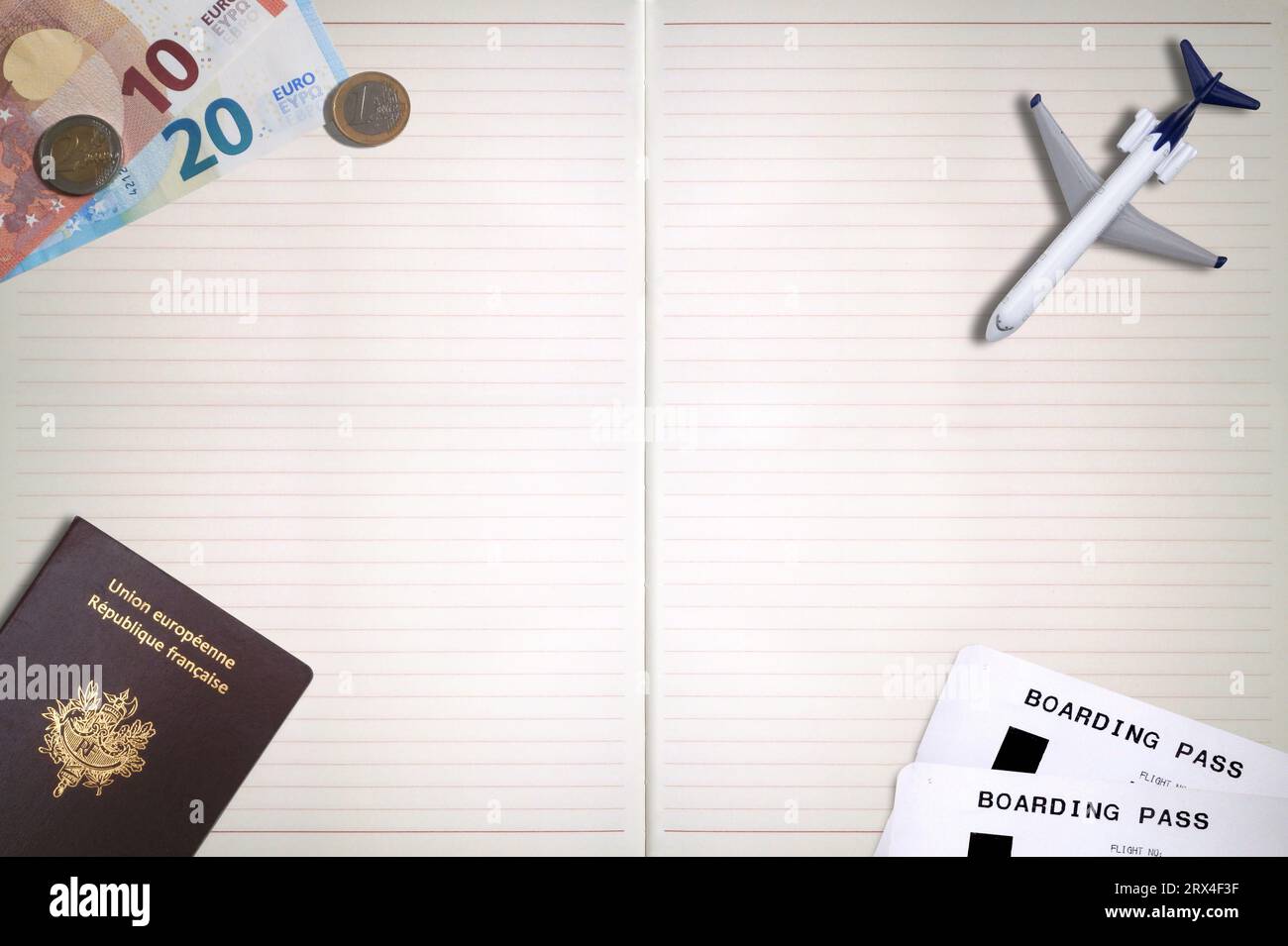 Un passeport français, deux billets d'avion, un avion jouet et quelques euros sur le dessus d'un bloc-notes avec espace de copie. Banque D'Images