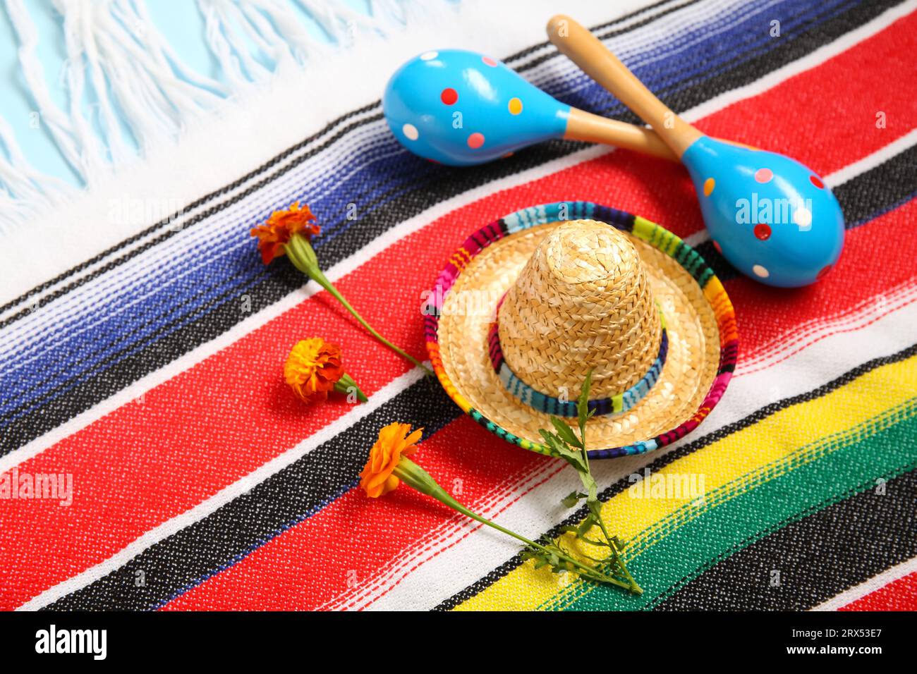 Poncho avec des fleurs, chapeau sombrero et maracas mexicains pour le jour de l'indépendance sur fond bleu, gros plan Banque D'Images