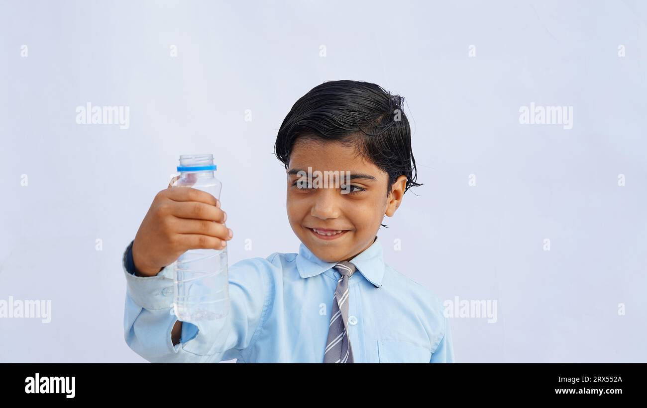 Les écoliers asiatiques boivent de l'eau d'une bouteille sur le fond du studio. Retour à l'école, concept de style de vie. Régime de consommation. Banque D'Images