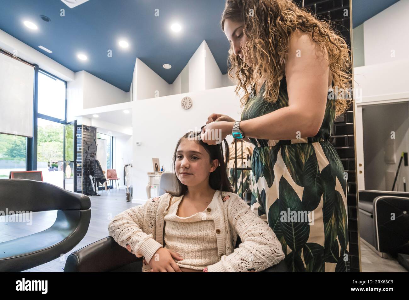 Coiffeur peignant les cheveux de fille au salon Banque D'Images