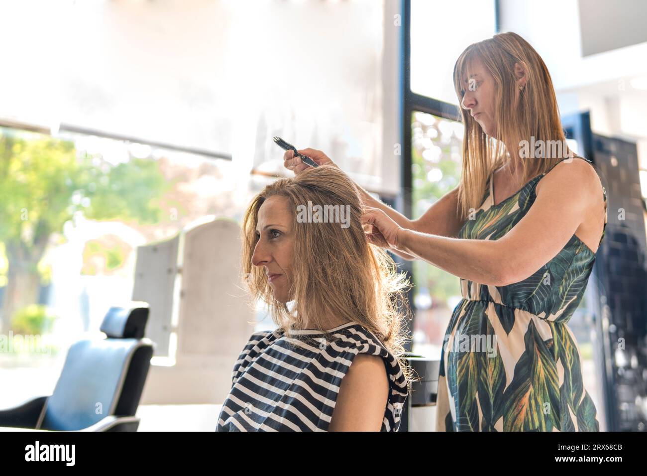 Coiffeur coiffant les cheveux de la femme au salon Banque D'Images
