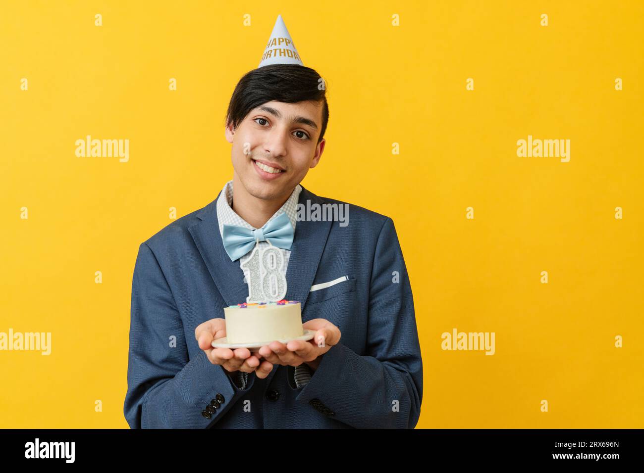 Homme souriant tenant le gâteau de 18e anniversaire dans le studio Banque D'Images