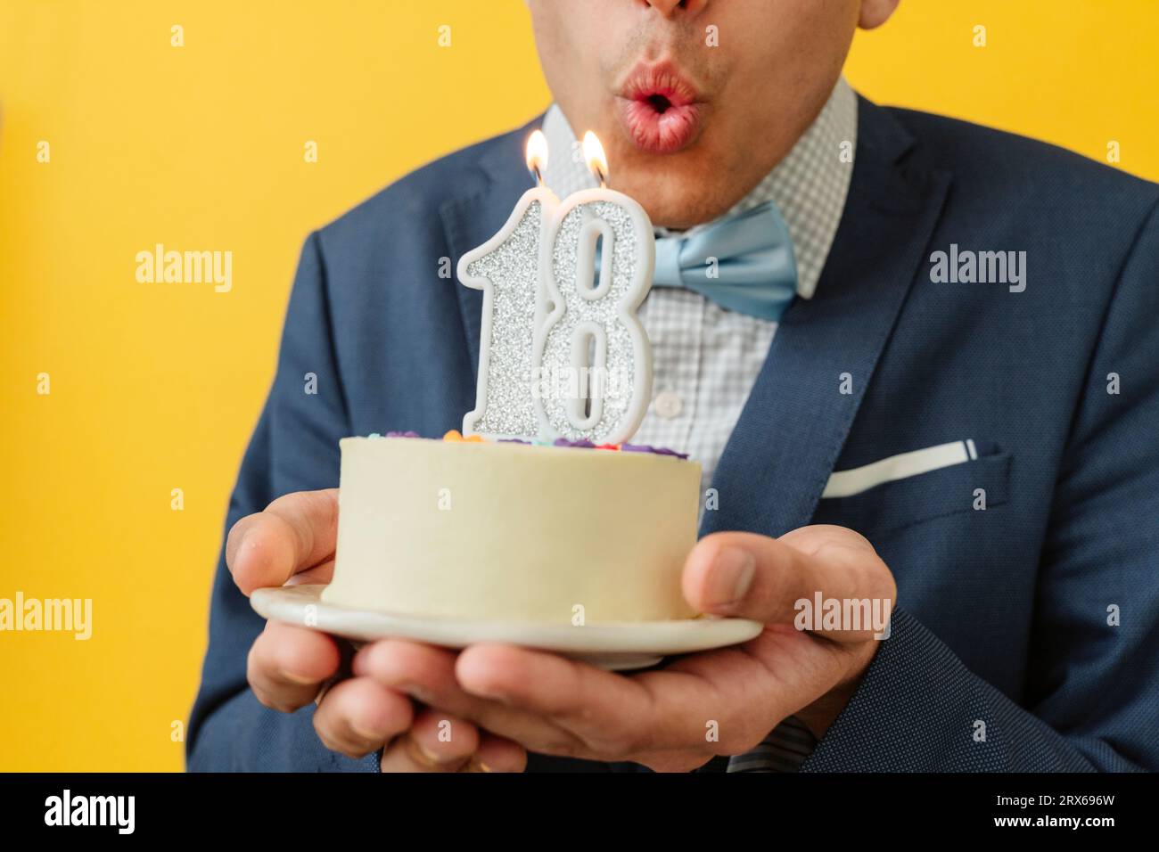 Homme soufflant la bougie du 18e anniversaire sur le gâteau Banque D'Images