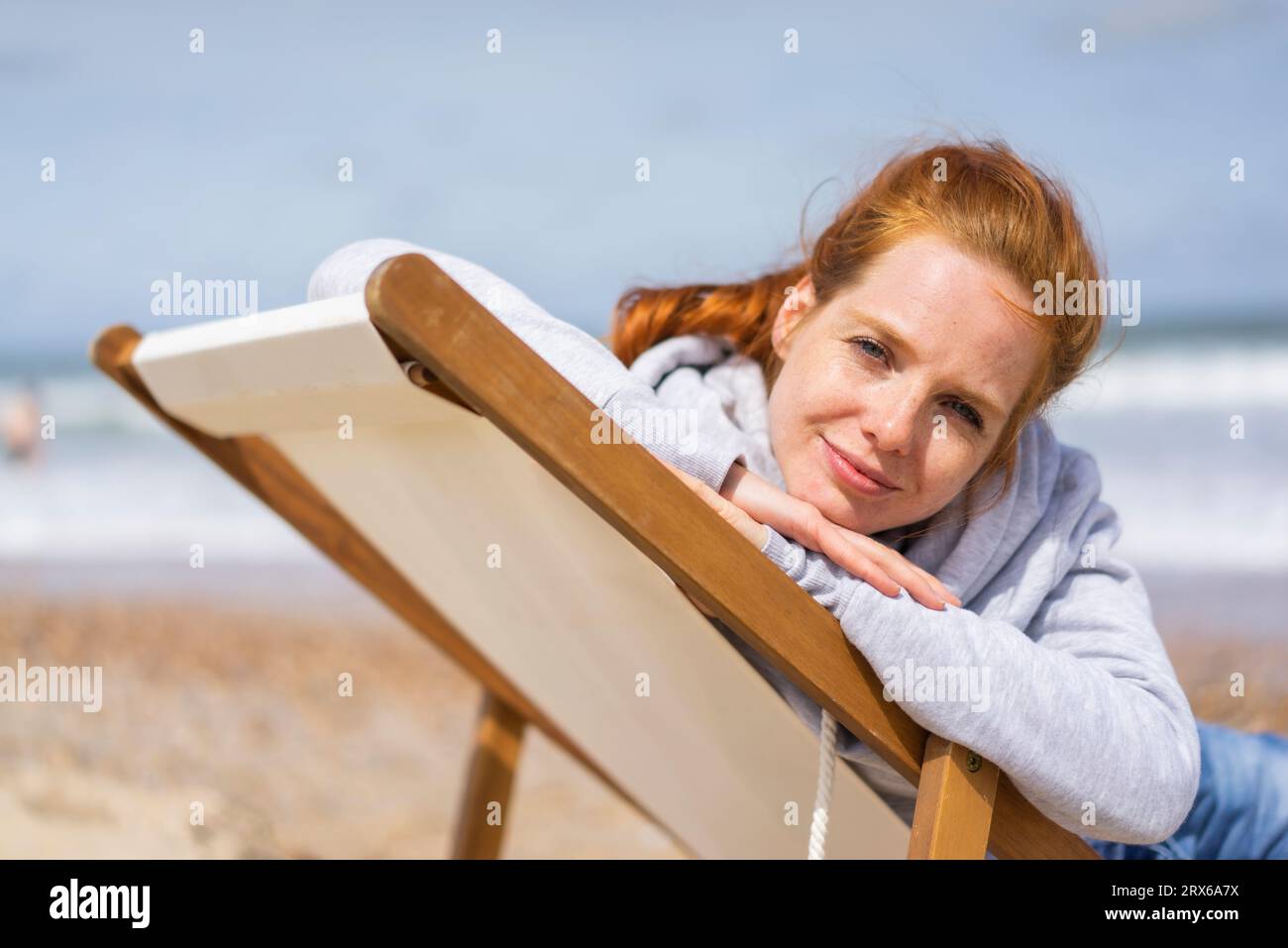 Femme se détendant sur une chaise longue à la plage Banque D'Images