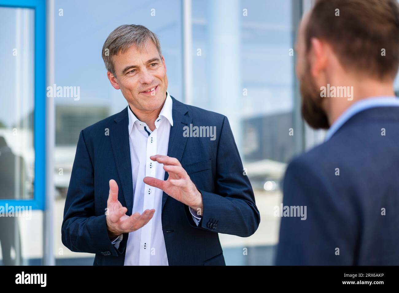 Homme d'affaires compétent écoutant collègue dans l'immeuble de bureaux Banque D'Images