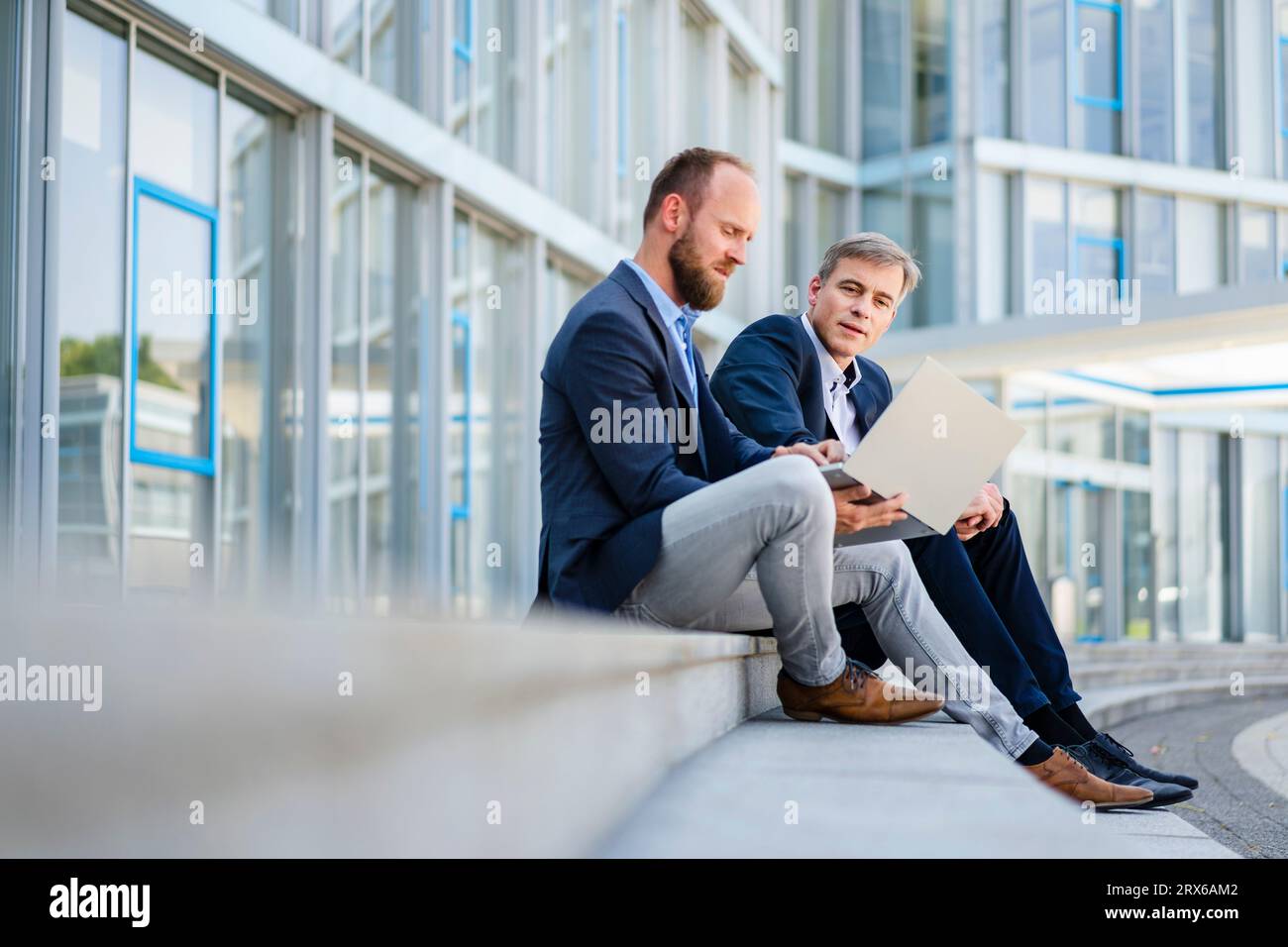 Deux collègues d'affaires assis sur des marches travaillant ensemble sur un ordinateur portable Banque D'Images