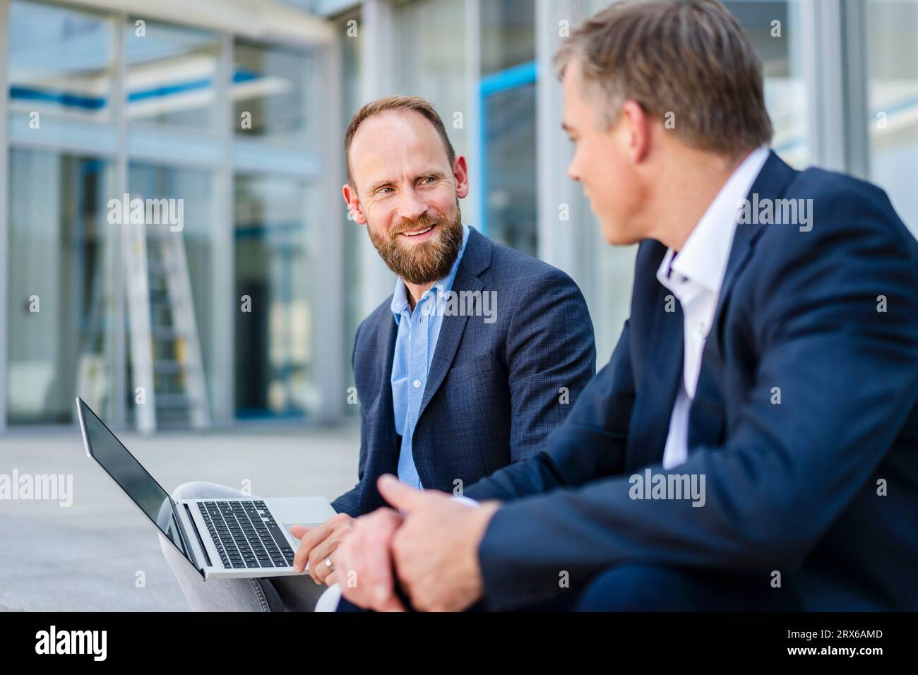 Deux collègues d'affaires assis sur des marches travaillant ensemble sur un ordinateur portable Banque D'Images