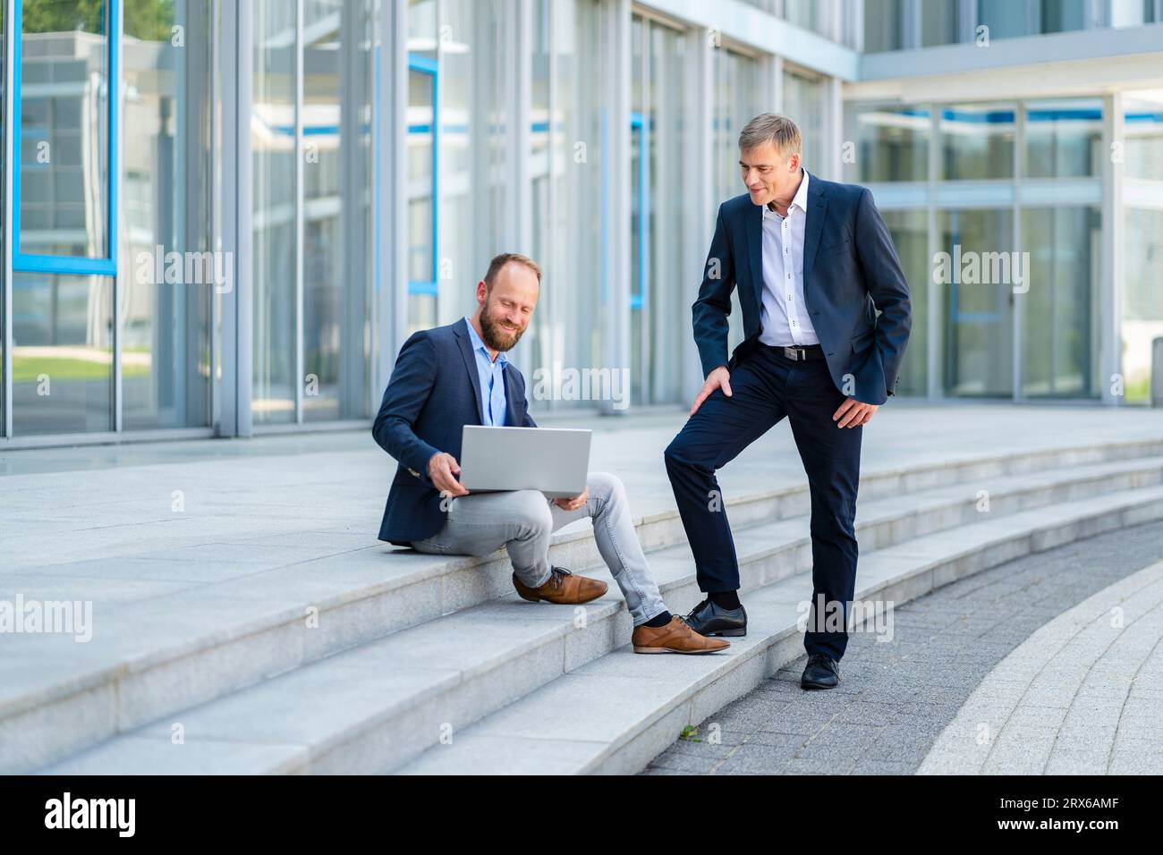 Deux hommes d'affaires travaillant ensemble sur ordinateur portable sur les marches de l'immeuble de bureaux Banque D'Images