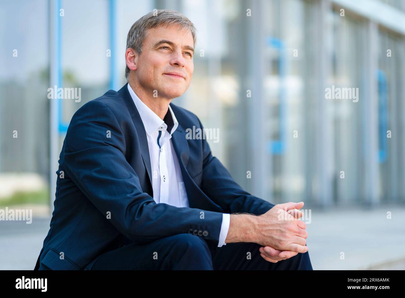 Homme d'affaires serein assis en face de l'immeuble de bureaux moderne Banque D'Images