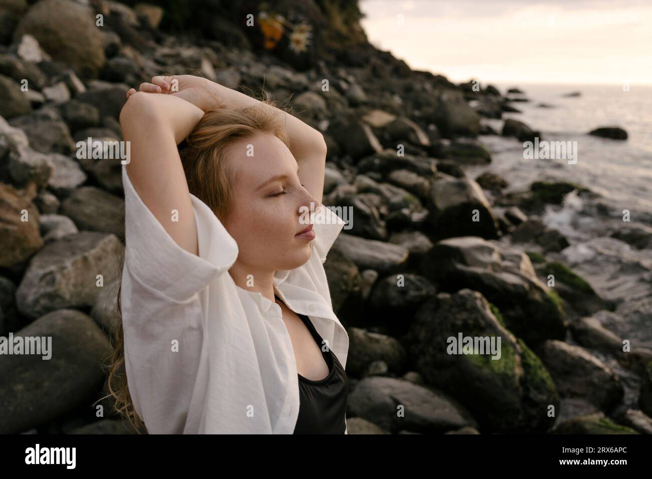 Jeune femme se détendant sur la plage au coucher du soleil Banque D'Images