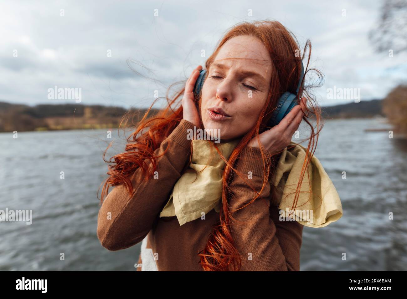 Femme avec les yeux fermés écoutant de la musique à travers des écouteurs sans fil Banque D'Images