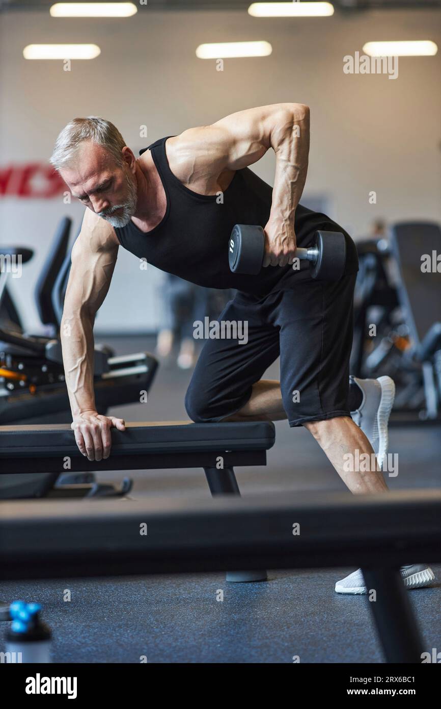 Homme mature faisant de la musculation avec haltère dans la salle de gym Banque D'Images
