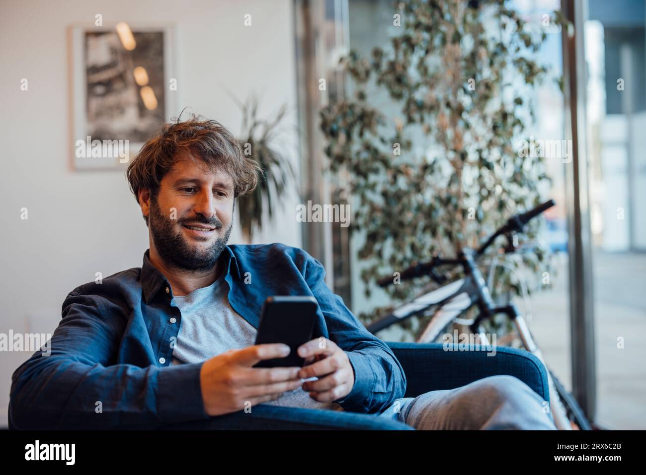 Smiling businessman using smart phone in office Banque D'Images