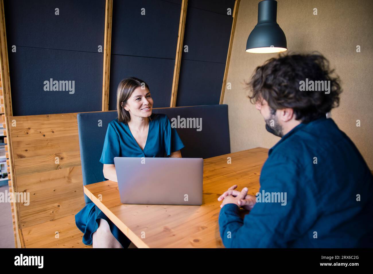 Souriant les gens d'affaires avec ordinateur portable ayant la discussion dans le bureau Banque D'Images