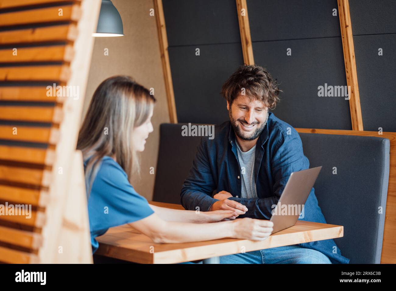 Femme d'affaires souriante discutant sur ordinateur portable avec l'homme d'affaires dans le cubicule de bureau Banque D'Images