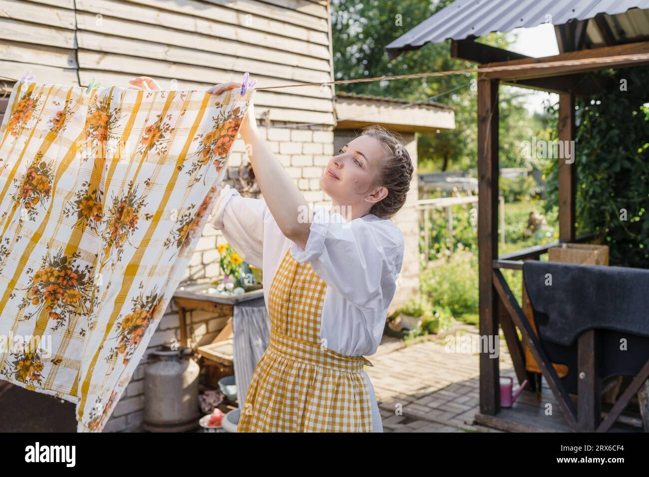 Femme pendante drap de lit pour sécher dans le jardin Banque D'Images