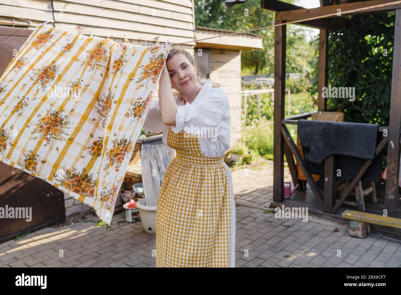 Femme souriante pendante drap de lit pour sécher dans le jardin Banque D'Images