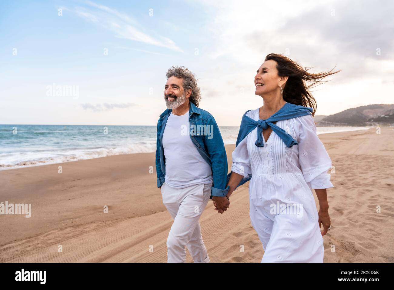 Heureux couple senior se tenant la main marchant à la plage Banque D'Images