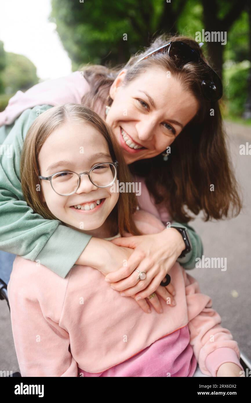 Mère souriante serrant sa fille dans le parc Banque D'Images