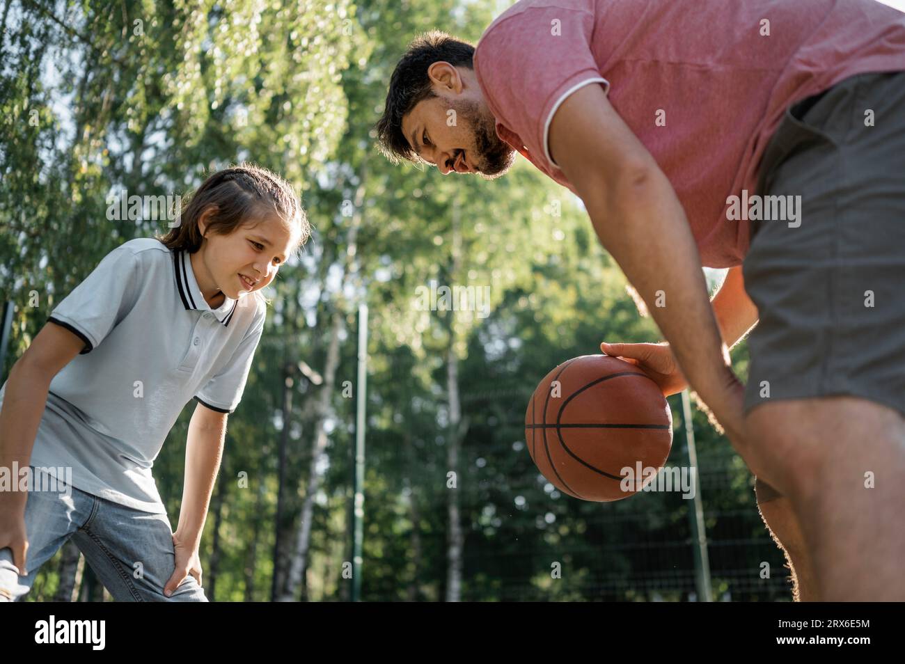 Père enseignant à son fils à dribbler le basket-ball Banque D'Images