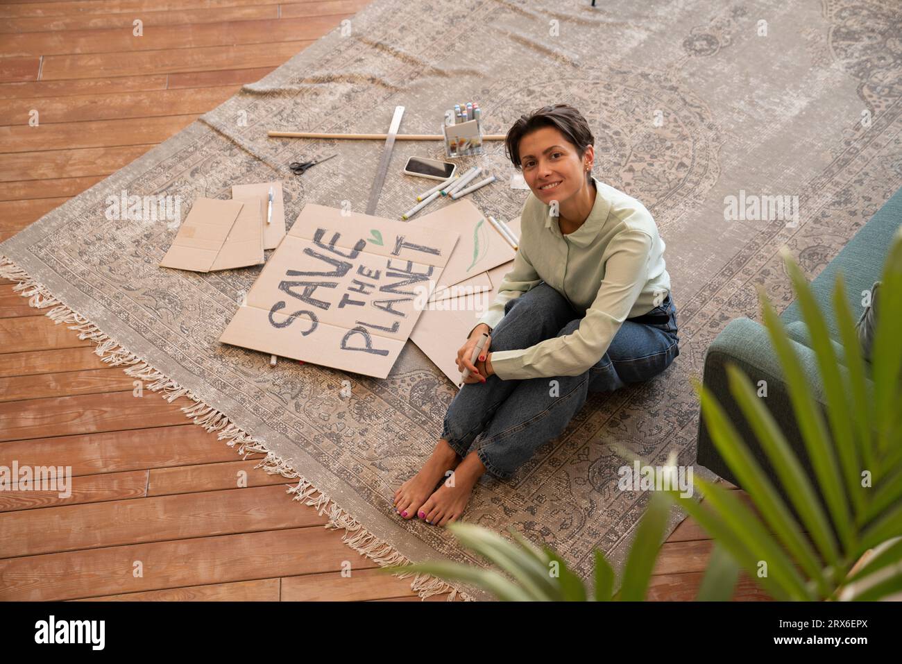 Activiste souriant préparant une pancarte sur le tapis à la maison Banque D'Images