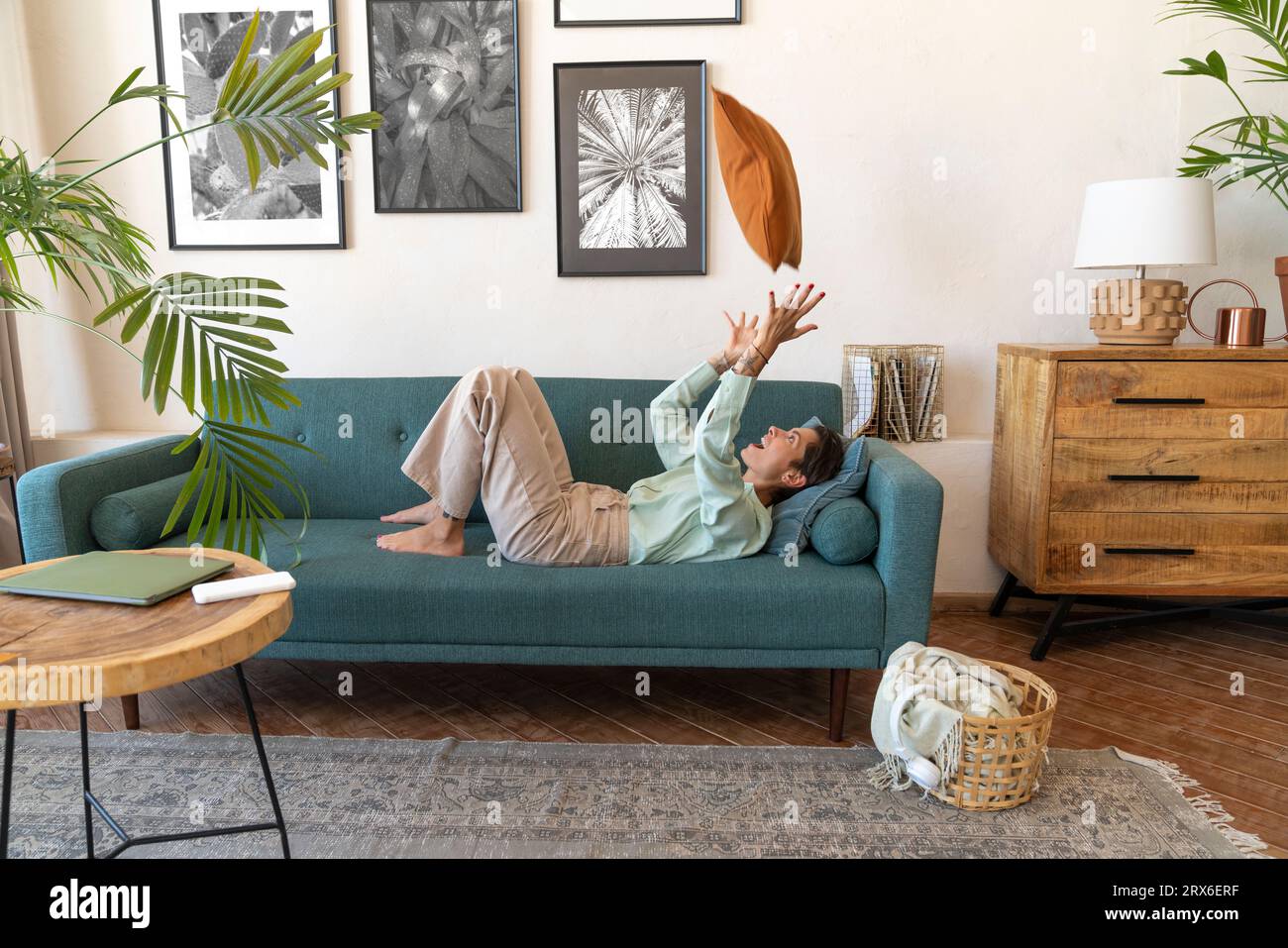 Femme joyeuse gestuant et se relaxant sur le canapé à la maison Banque D'Images