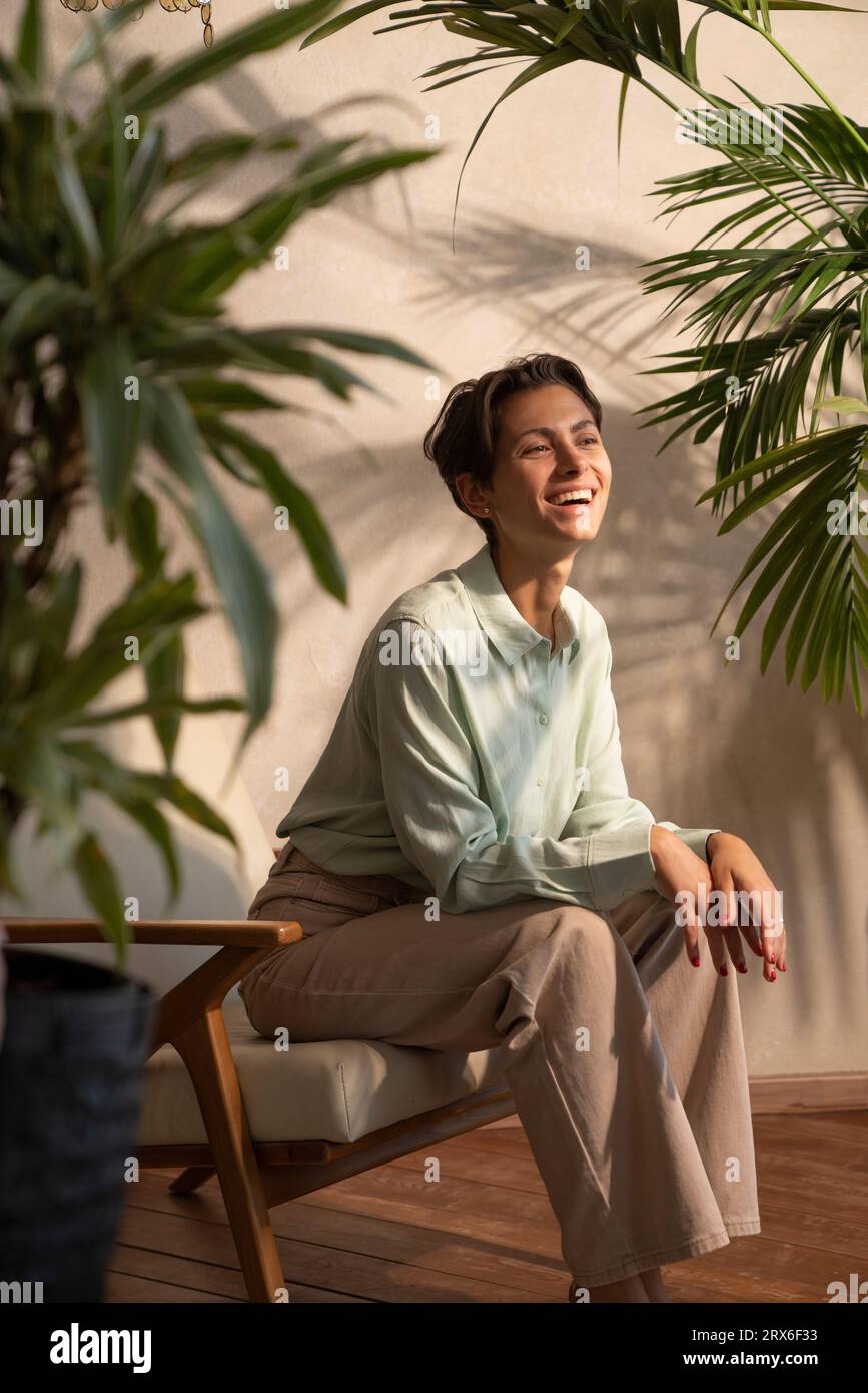 Femme souriante assise dans un fauteuil au milieu des plantes Banque D'Images