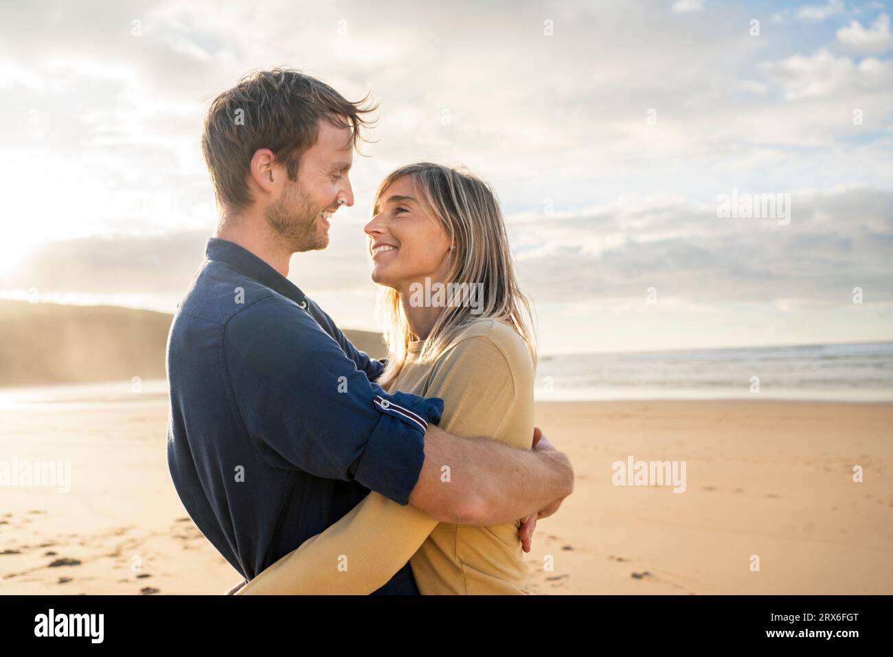Femme souriante avec un homme s'embrassant à la plage Banque D'Images