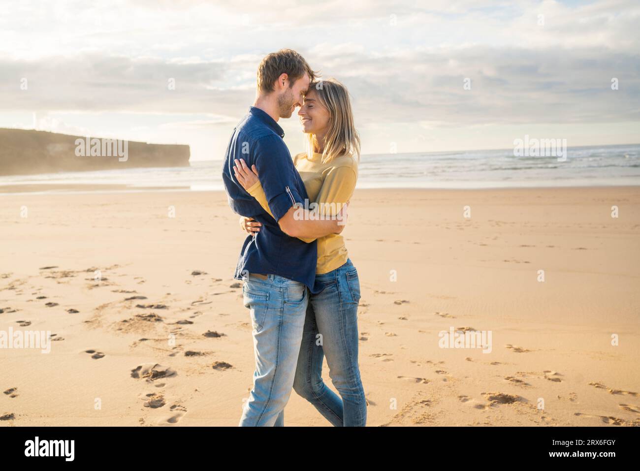 Homme et femme heureux s'embrassant devant la mer à la plage Banque D'Images