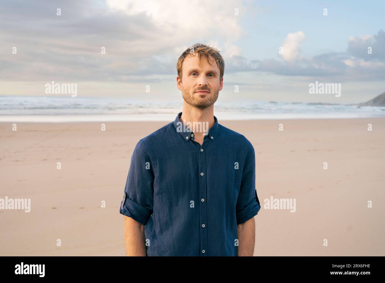 Homme souriant debout devant la mer à la plage Banque D'Images