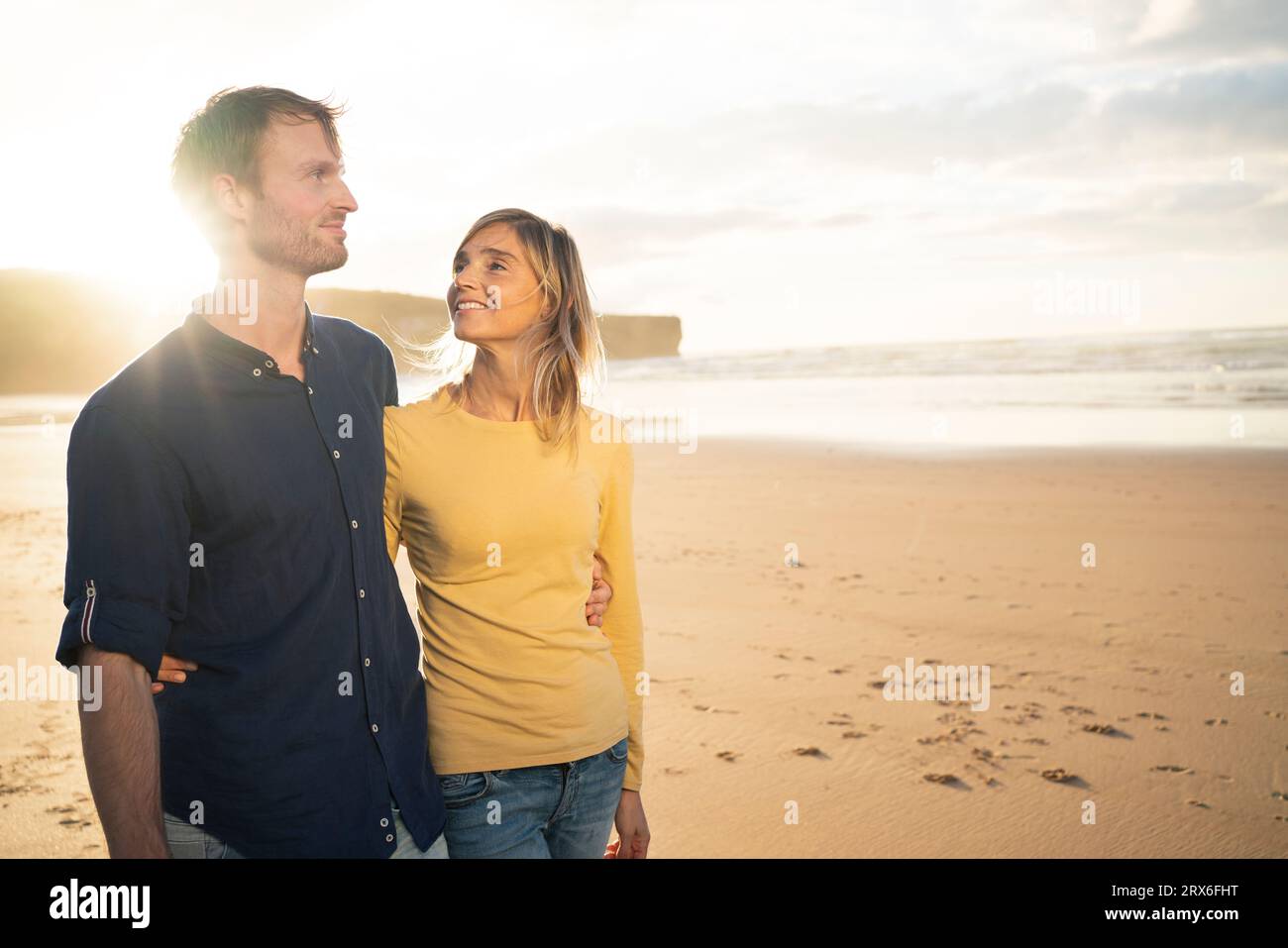 Couple heureux debout au coucher du soleil en face de la mer Banque D'Images Couple heureux debout au coucher du soleil en face de la mer Banque D'Images