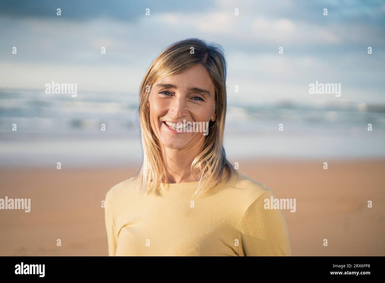 Femme blonde souriante à la plage Banque D'Images